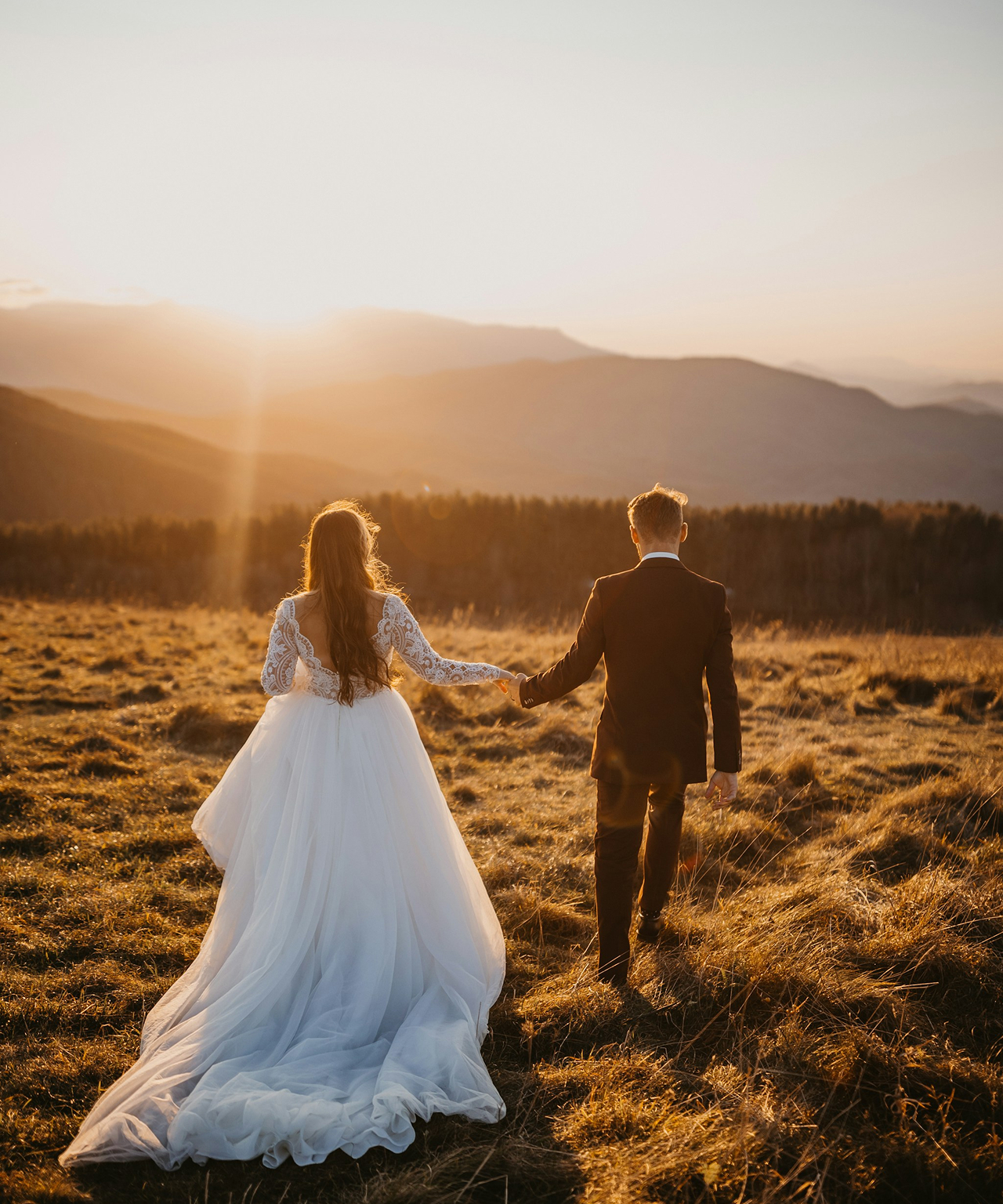 Bride and groom walking together at sunset
